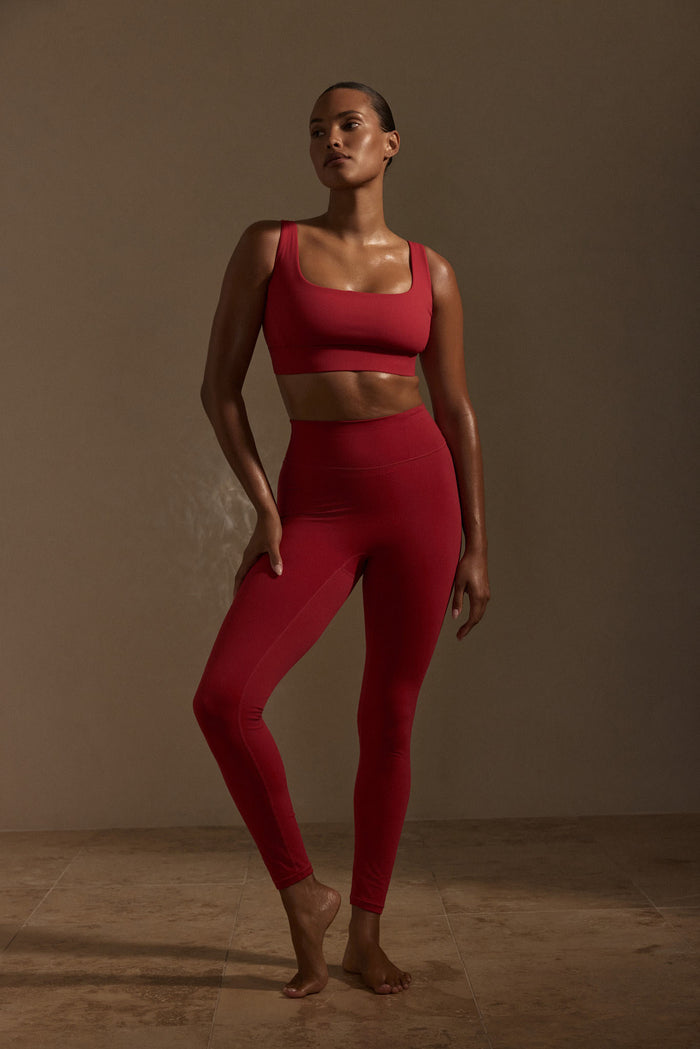 Three-quarter view of Acadia Legging Long in Cherry showing high waist and front pocket on model in neutral studio