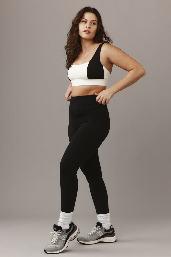 Three-quarter view of Acadia Long Legging 29-inch in black showing high-rise wide waistband and full-length fit on model against neutral background