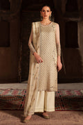 Woman wearing a traditional outfit with intricate patterns in a warm-toned setting.