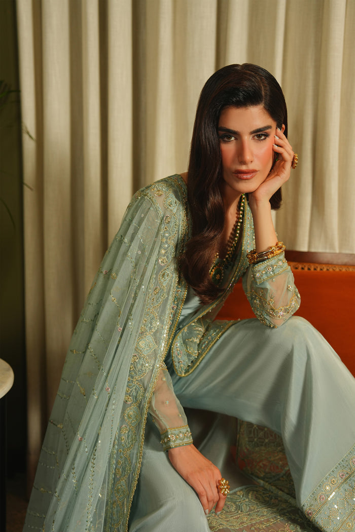 Close seated view of NAQSHI Alyana dusty blue outfit highlighting rich embroidery, soft fabric fall, and refined event wear look.