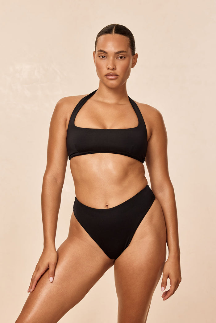 Front of Amalfi Top in black on model showing square neckline, halter ties and structured fit on beige background