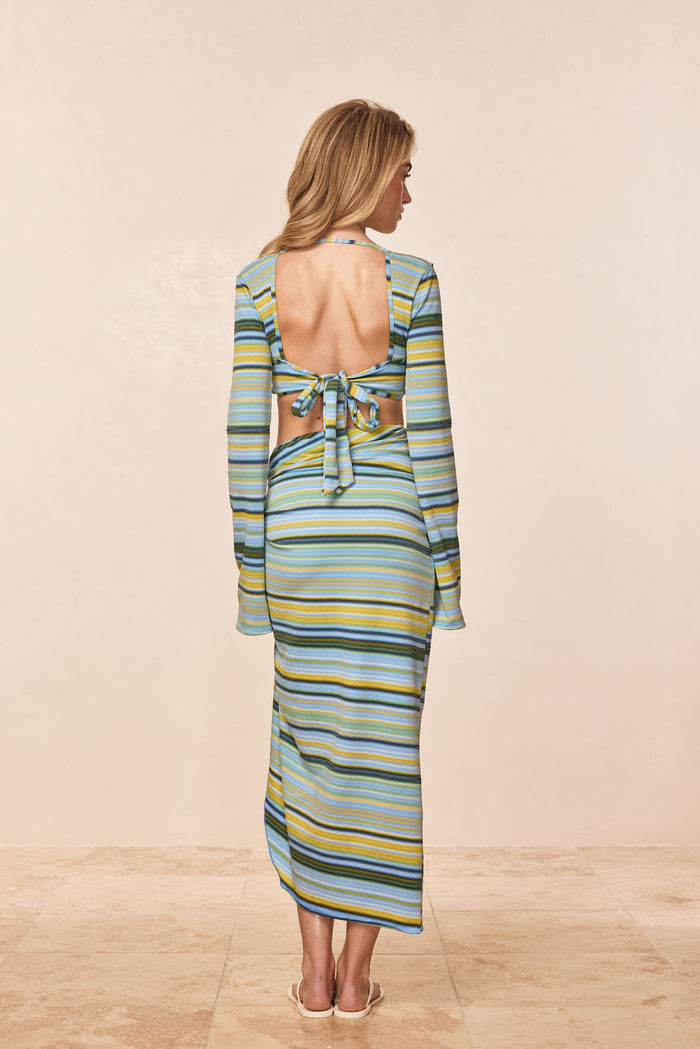 Back view of Andros Sarong in Sardinia Stripe Azure showing knotted back tie, open back, and floor-length striped fabric on a beige studio background