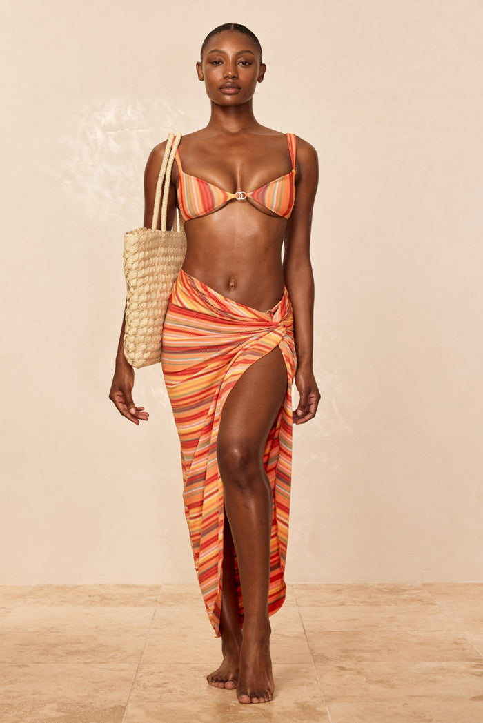 Front view of Andros Sarong in Sardinia Stripe showcasing high thigh slit and knotted waist on model against beige studio background