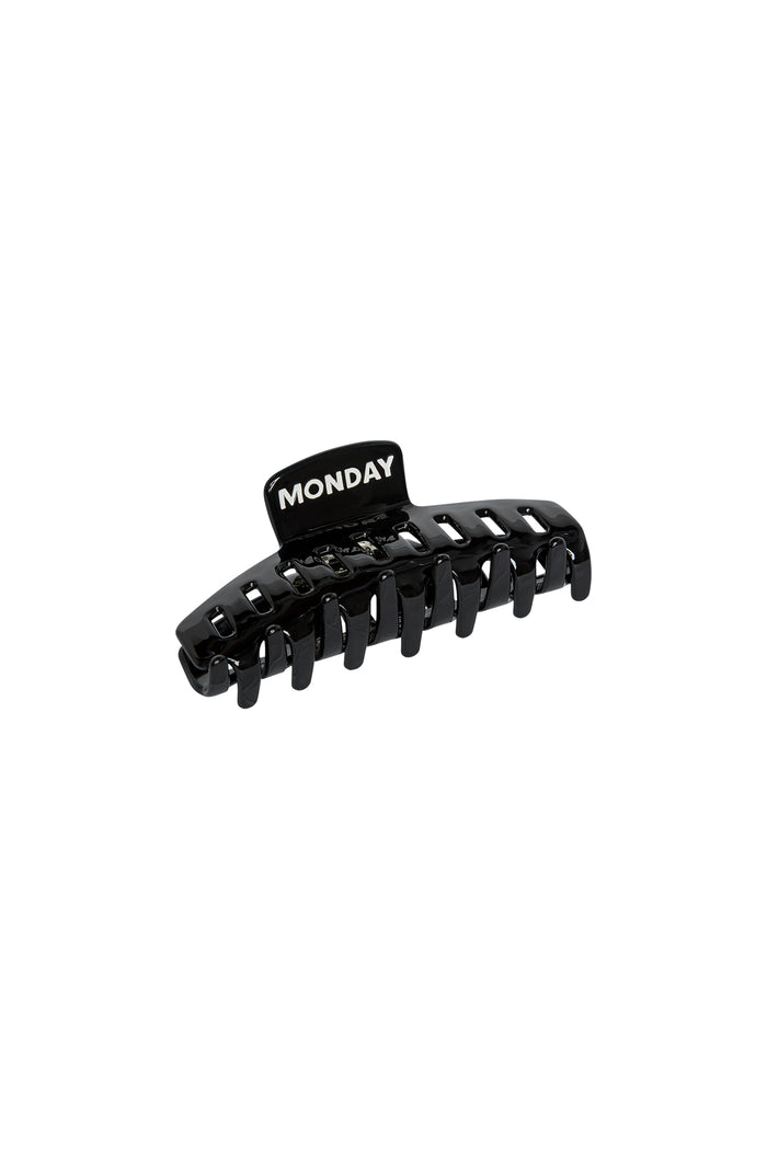 Black plastic hair claw clip with tab labeled MONDAY