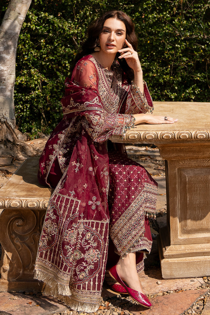 Seated view of NAQSHI Azra maroon formal outfit highlighting dupatta borders, lace trim details, and polished wedding-ready look.