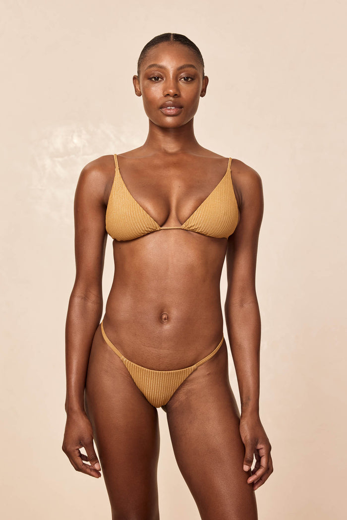 Front view of Barbados Bottom in Antique Gold Lurex Rib showcasing ribbed shimmer and high-cut thong on beige background