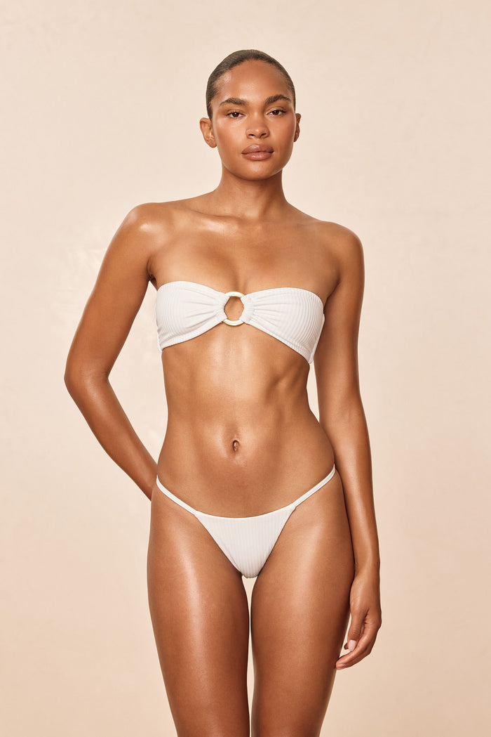 Front view of Barbados Bottom - White Rib showcasing thin side straps and minimal coverage on a model against a neutral beige background