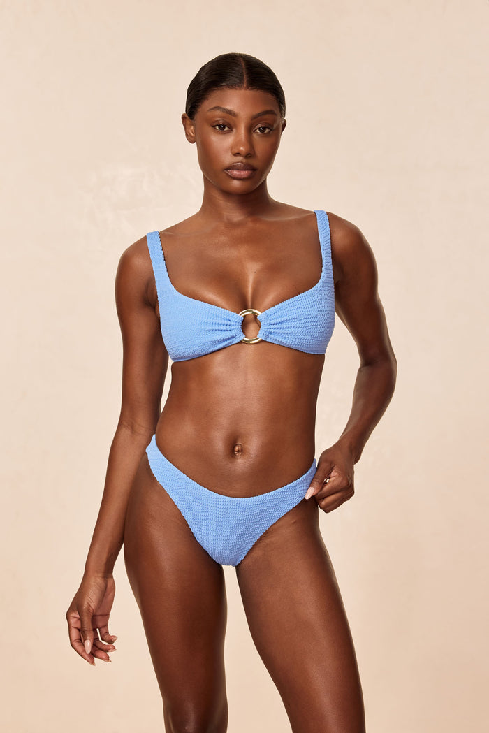 Front view of Byron Bottom in Azure Crinkle on model, high-cut V-front and textured fabric on beige background