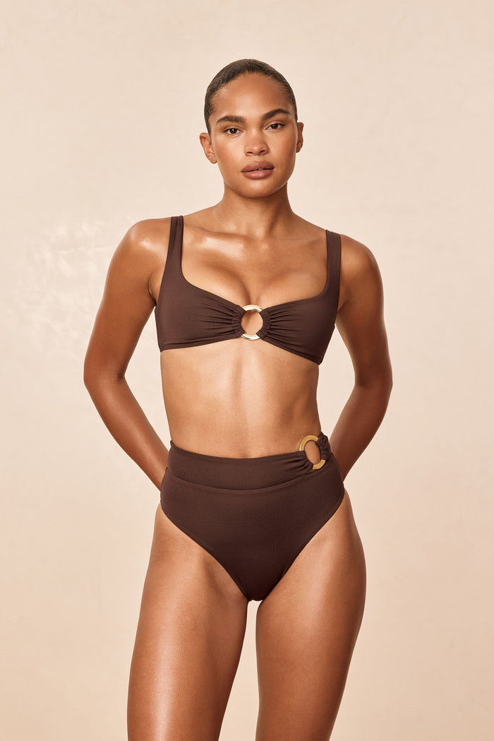 Front view of Barbuda Top in Espresso on model showcasing wide straps and gold center ring with neutral beige studio background