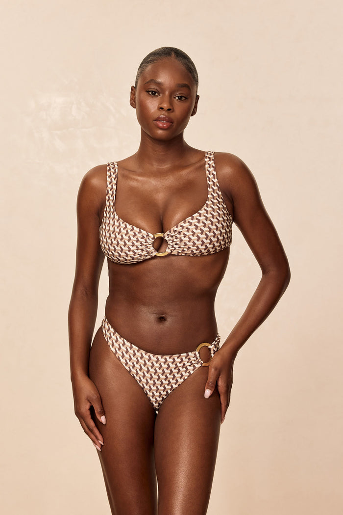 Front view of Barbuda Top bikini in Husk Geo showcasing scoop cups and center ring hardware on model with beige background