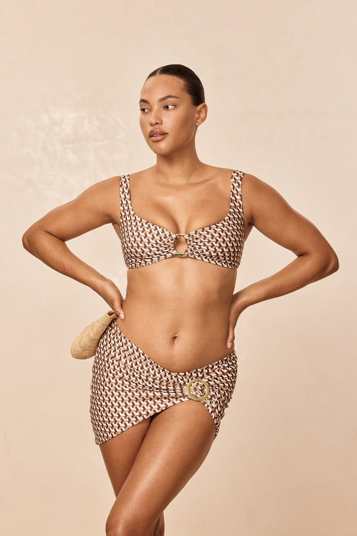 Front view of Barbuda Top in Husk Geo with scoop neckline, center gold ring and wide straps on beige background