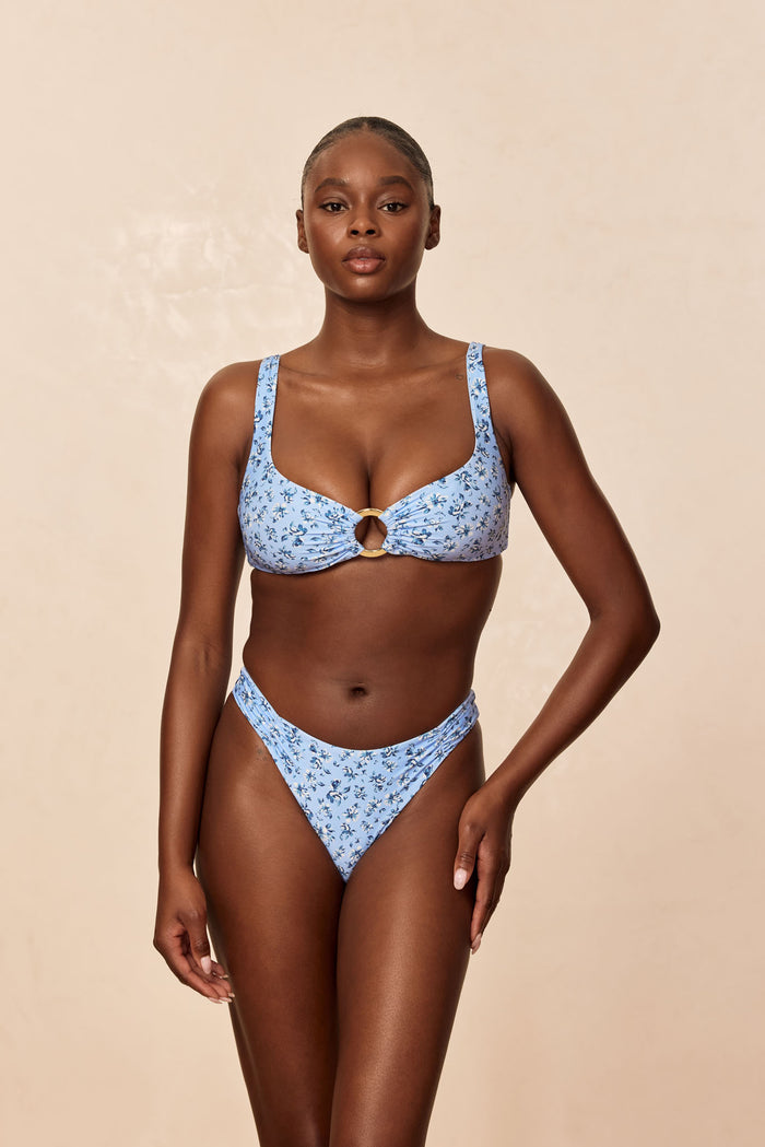 Front view of Barbuda Top in Isola Floral on model showing over-the-shoulder straps, gold front ring, beige background