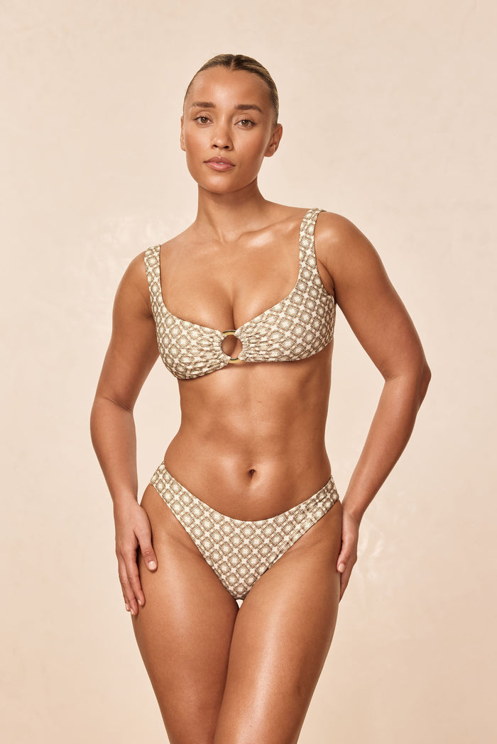 Front of Barbuda Top in Tile Geo on model showing scoop neckline, center ring and wide straps on beige background