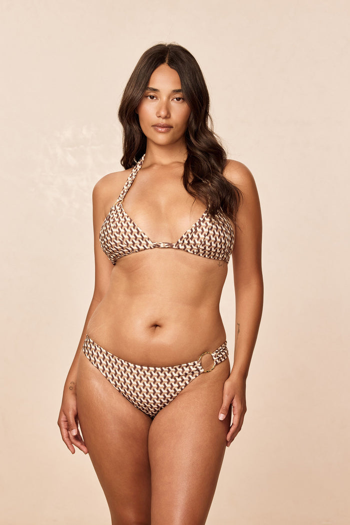 Front view of Bari Bottom in Husk Geo brown and cream print, mid-rise with side ring detail on model against beige background