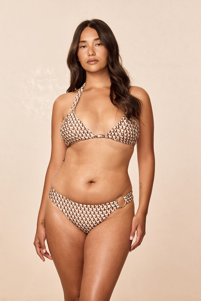 Front view of Bari Top in Husk Geo brown geometric print on model, halter triangle cups with center tie and neutral beige studio background