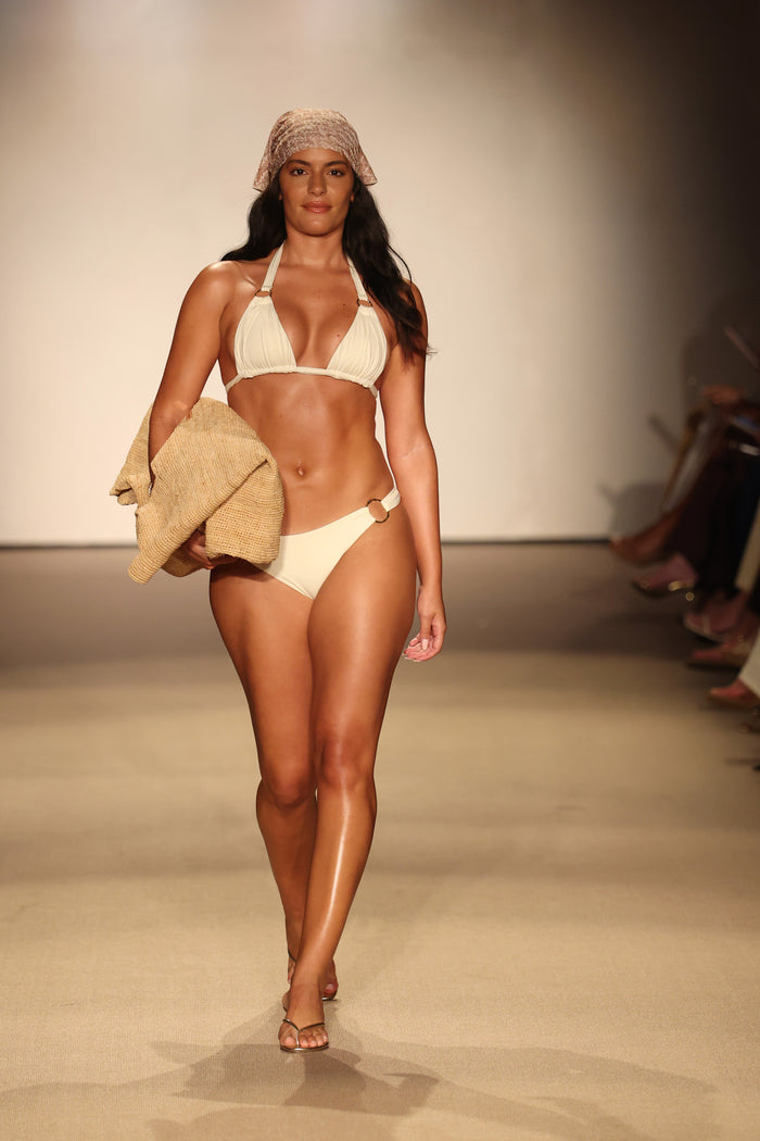 Front view of Bari Bottom in ivory on model showing mid-rise fit, high-cut leg, cheeky coverage and organic gold ring detail on runway
