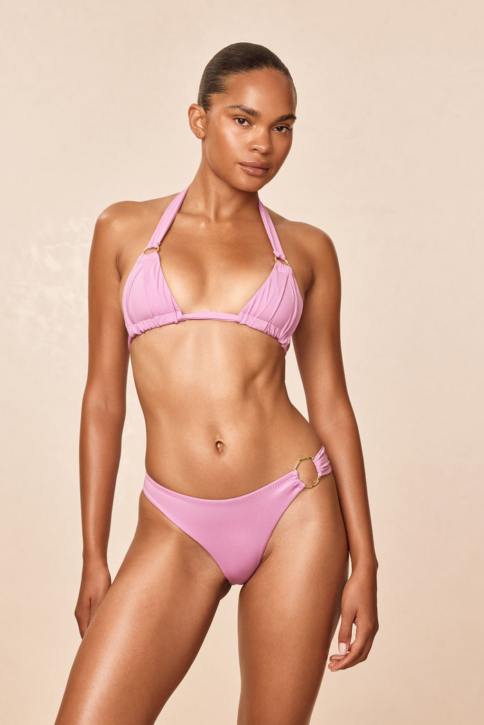 Front view of Bari Top - Moonlight on model showing pleated cups and gold ring detail on beige background