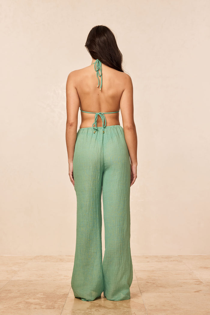 Back view of Belize pant in Pond Crinkle Linen, elastic high waist and wide-leg silhouette on beige background