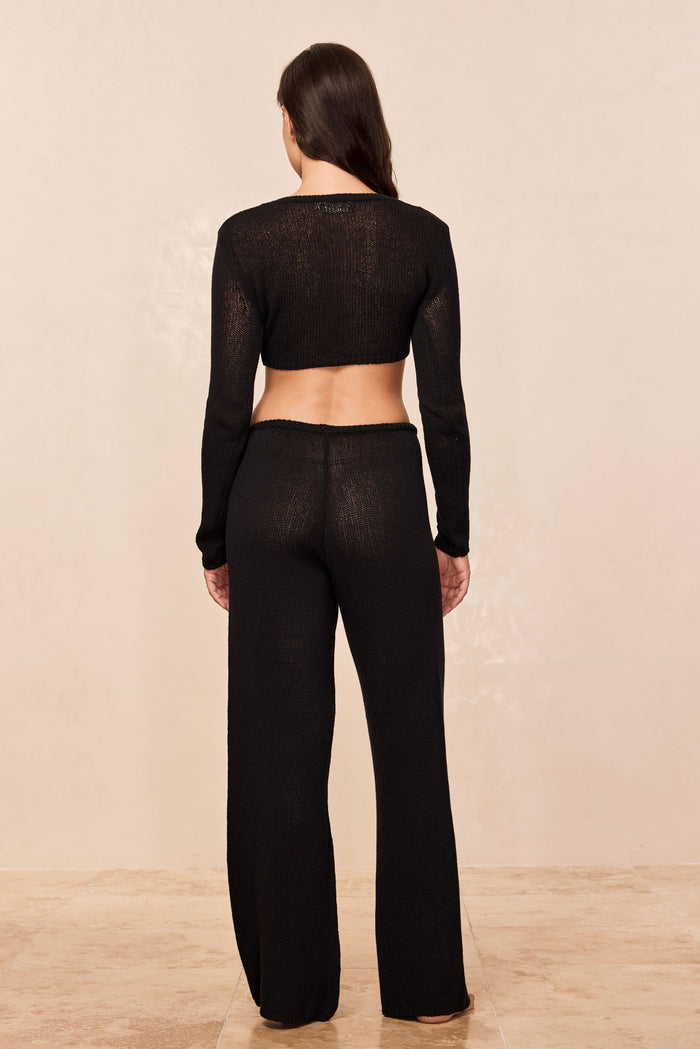 Rear view of Belize Pant open knit in black showcasing high waist and wide leg silhouette with matching cropped knit top on neutral backdrop