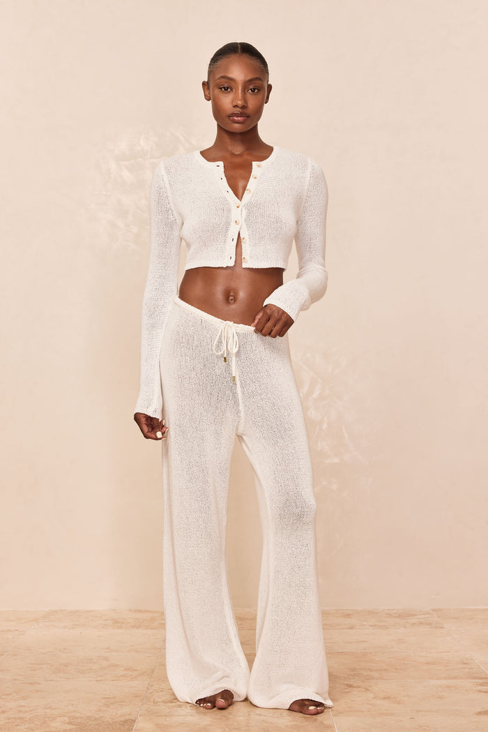 Front view of Belize Pant Open Knit in Ivory on model showing sheer open-knit wide-leg pants with drawstring waist, beige backdrop