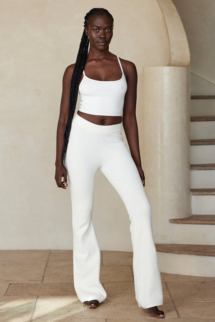 Front view of Beverly Hills Knitwear Top in White Rib showing thin straps and cropped ribbed fit against curved stone staircase