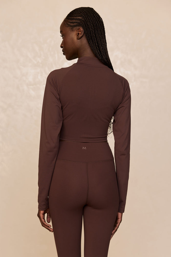 Rear view of Big Sur Jacket in Espresso showcasing cropped fit and long sleeves on model against beige studio background