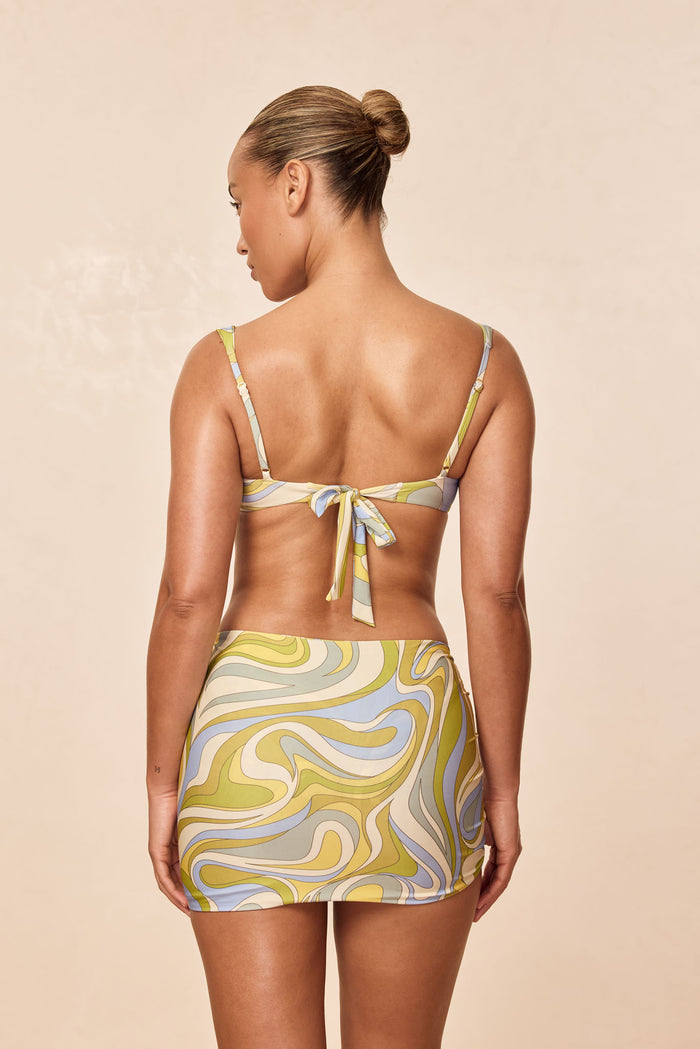 Rear view of Bimini Skirt in Costa Rei Apple print on model, fitted mini with multicolor swirl pattern on beige background