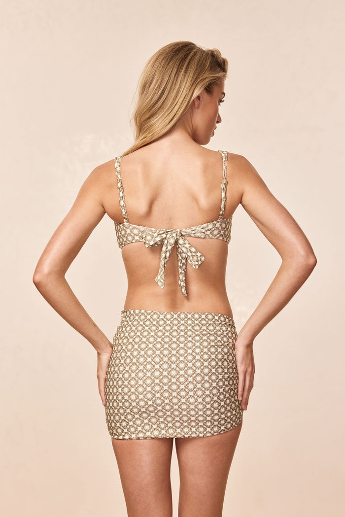 Back view of Bimini Skirt - Tile Geo showcasing side rouched detail and mini length with beige studio background
