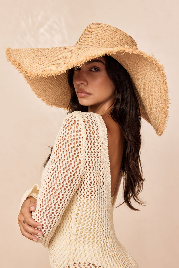 Three-quarter view of Bondi Hat - Wide Brim in straw showing large frayed brim on model against neutral background