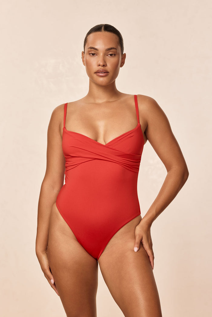 Front of Bordeaux one-piece in Chili Pepper on model with crossover bodice, adjustable straps, high-cut leg