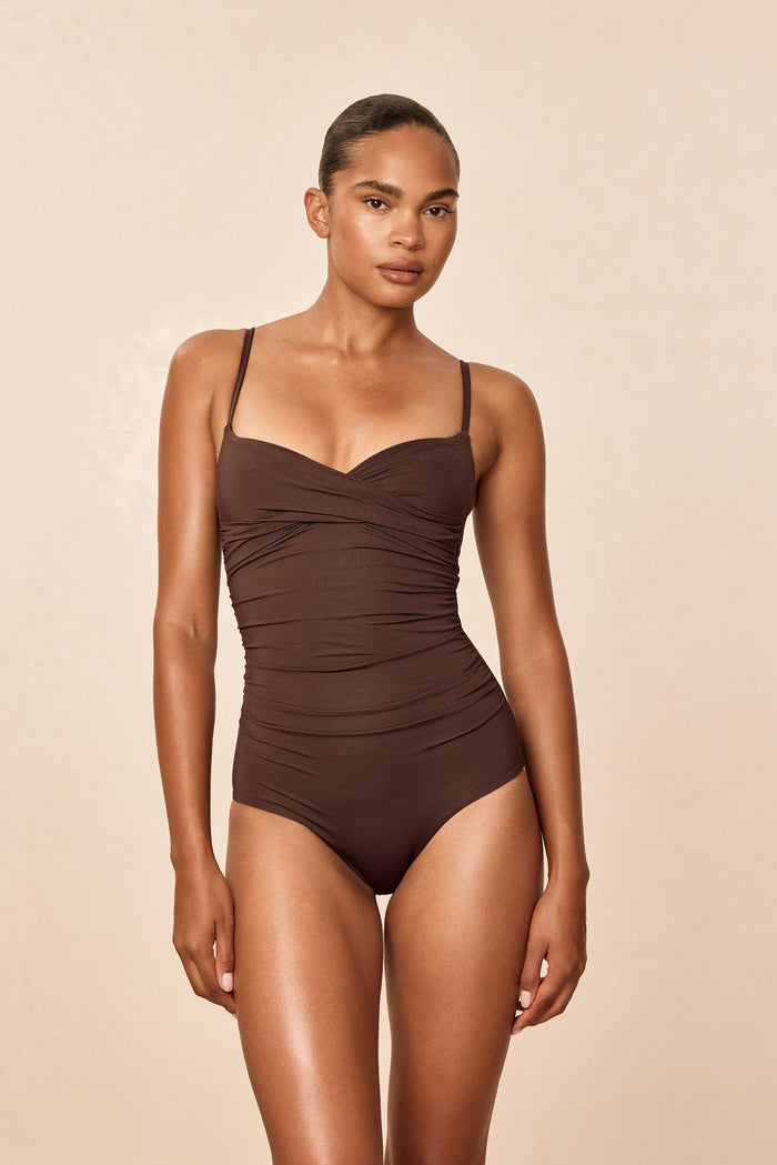 Front of Bordeaux swimsuit in Espresso with crossover neckline, adjustable straps and ruching on neutral background