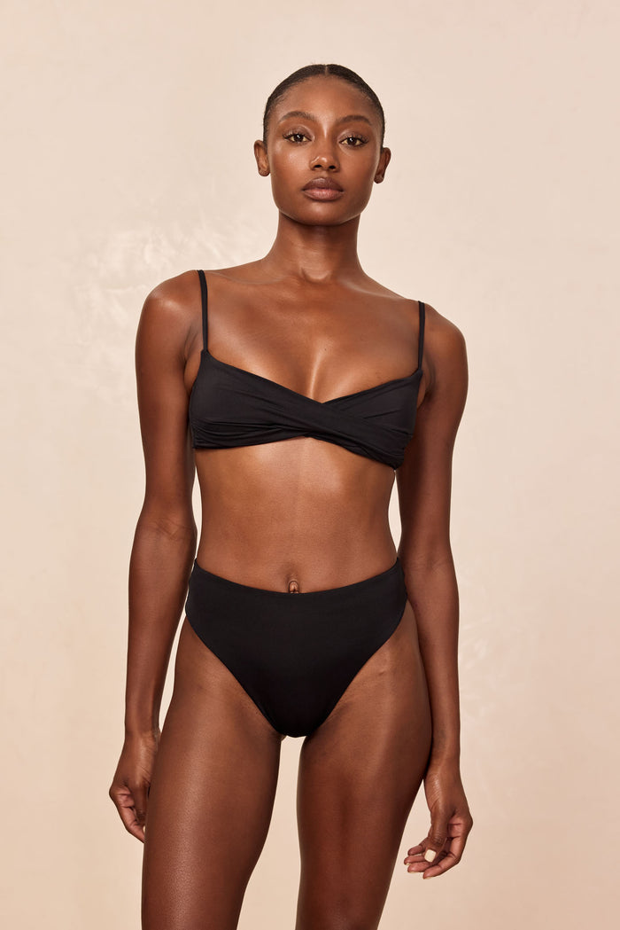 Front view of Bordeaux Top in black on model showcasing twist-front detail and thin adjustable shoulder straps, neutral background