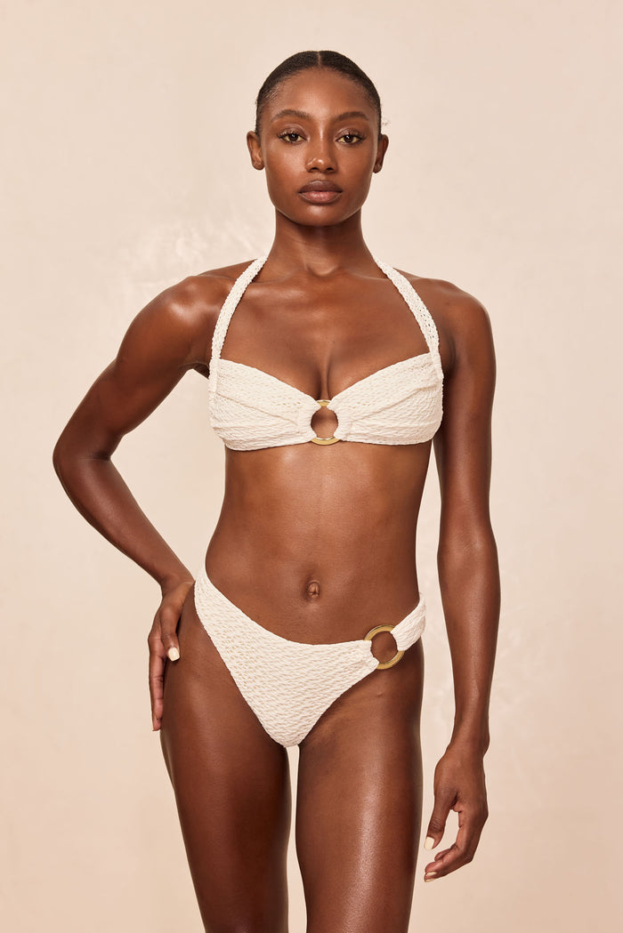 Front view of Bronte Bottom in Ivory Crochet on model with textured crochet fabric and gold side ring against beige background