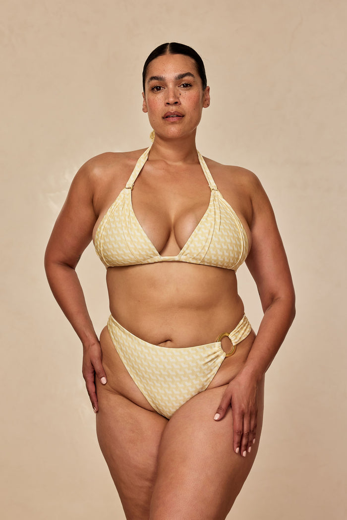 Front view of Morocco Top in Ivory Geo on model showing triangle halter, gold ring hardware, and geometric print on beige backdrop