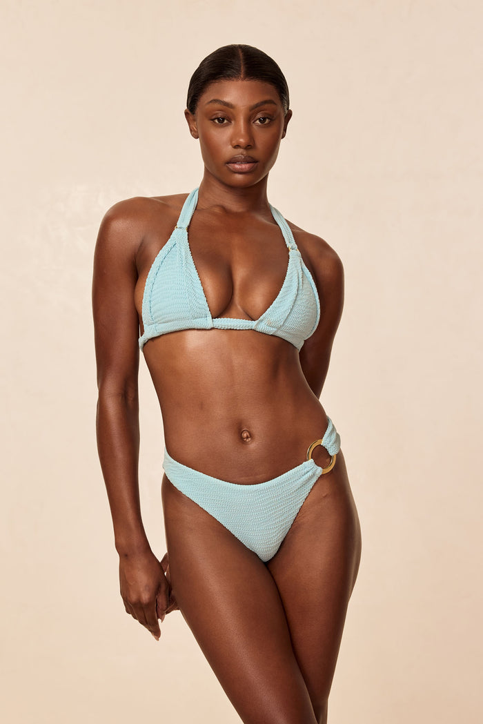 Front view of Bronte Bottom in Light Slate Crinkle showcasing crinkle texture, high-cut hip and gold side ring on a beige background