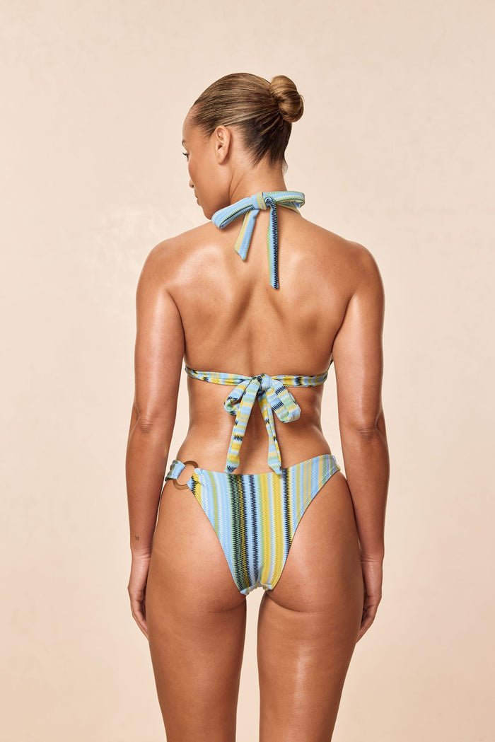 Back of Morocco Top in Sardinia Stripe Azure with halter neck and back ties and gold ring hardware on beige background