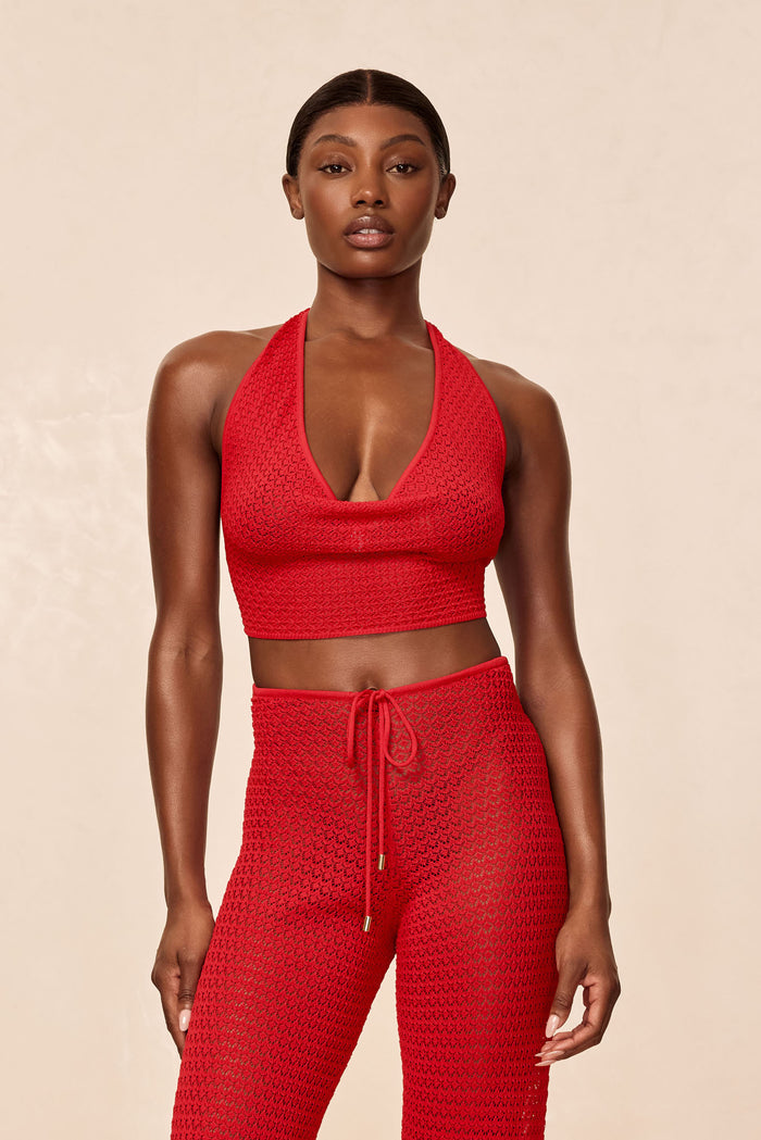 Front view of Bula Cowl Neck Top in Chili Pepper red on model showcasing cowl halter neckline and crochet lace texture with beige backdrop