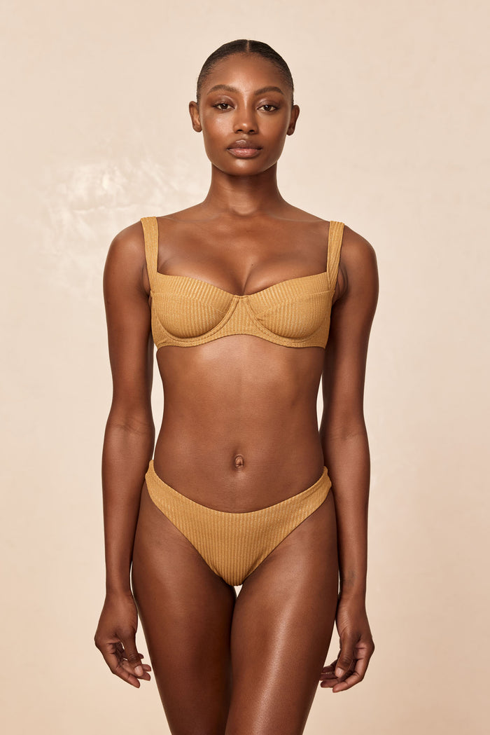 Front view of Byron Bottom in Antique Gold Lurex Rib on model showcasing ribbed shimmer fabric and V-front cut against a neutral beige background