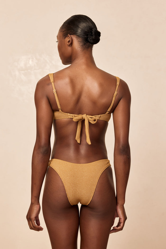 Back view of Byron Bottom in Antique Gold Lurex Rib showcasing ribbed lurex shimmer and moderate coverage on beige background