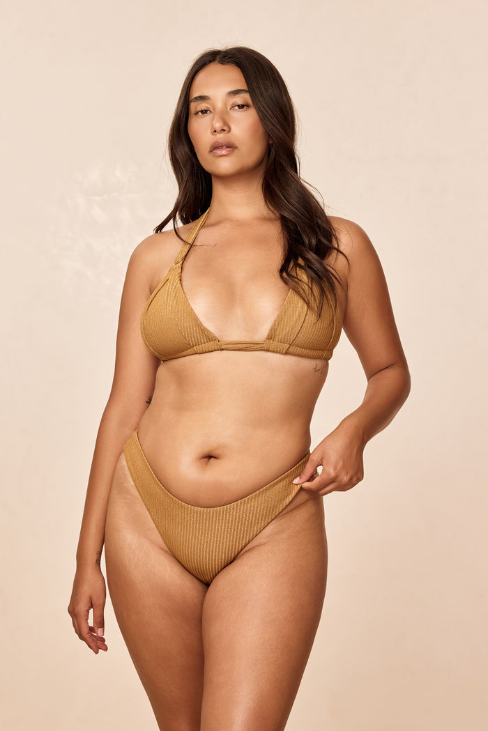 Front view of Byron Bottom in Antique Gold Lurex Rib showcasing mid-rise fit and cheeky coverage in ribbed shimmer fabric on beige background