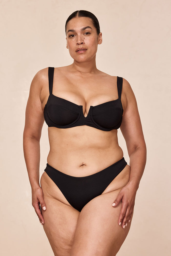 Front of Clovelly Top in black on a plus-size model showing underwire balconette cups, plunge V-front and adjustable straps