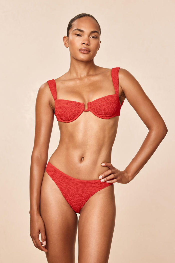 Front view of Byron Bottom in Chili Pepper Crinkle on model showing mid-rise fit, cheeky coverage and crinkle texture against a beige background