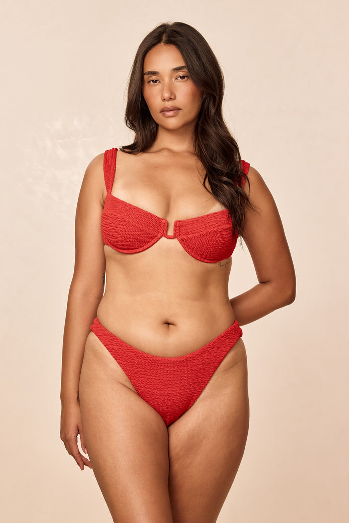 Front view of Byron Bottom in Chili Pepper Crinkle showing high-cut, textured red bikini bottom on model against beige background