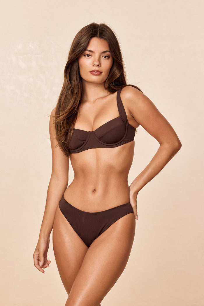 Three-quarter front of Byron Bottom in espresso showing ribbed texture and mid-rise coverage on model with beige background