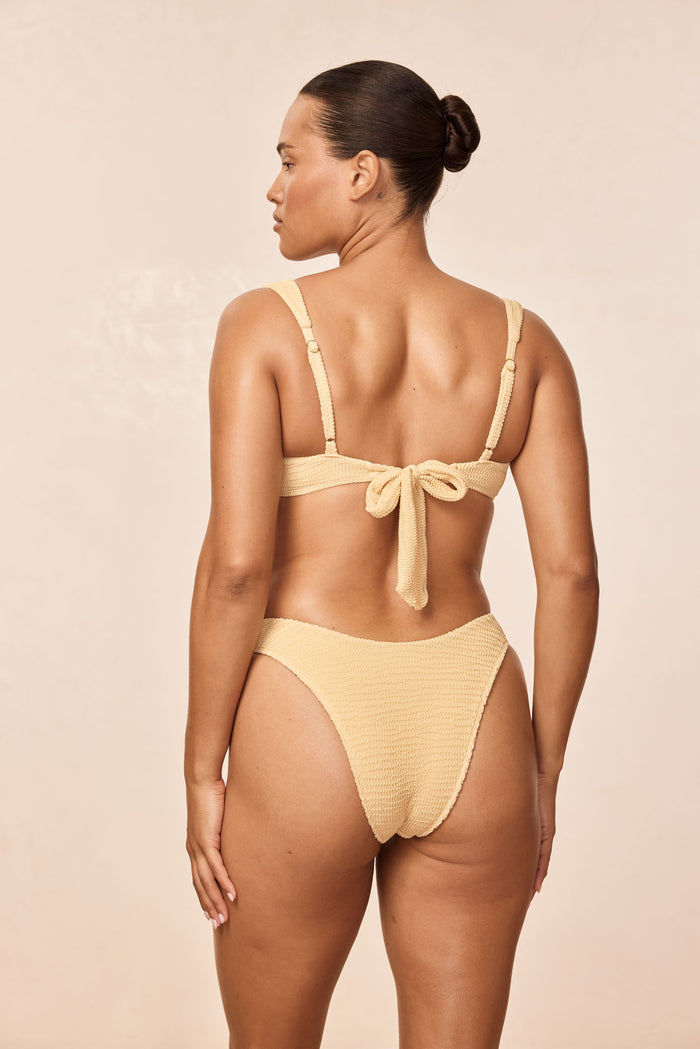 Back view of Byron Bottom in Raffia Crinkle showing high-cut, textured fabric on model against a neutral beige background