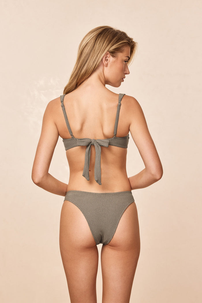 Rear view of Byron Bottom in Steel Lurex Rib showing ribbed texture, mid-rise fit and cheeky coverage on beige background