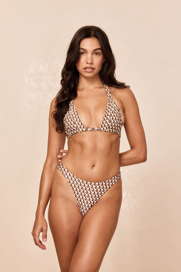 Front view of Byron Thong Husk Geo thong showing high-cut silhouette and brown and ivory geometric print on beige background