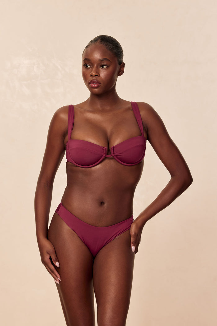 Front view of Cala Roja top in Fig showcasing underwire balconette shape with molded cups and wide straps against a beige studio background