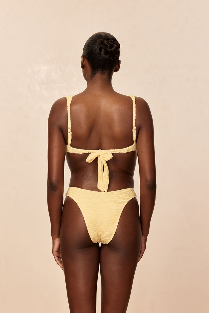 Rear view of Cala Roja Top in Honey Crinkle with matching high‑leg bottoms, showing tie-back and crinkle texture on beige background