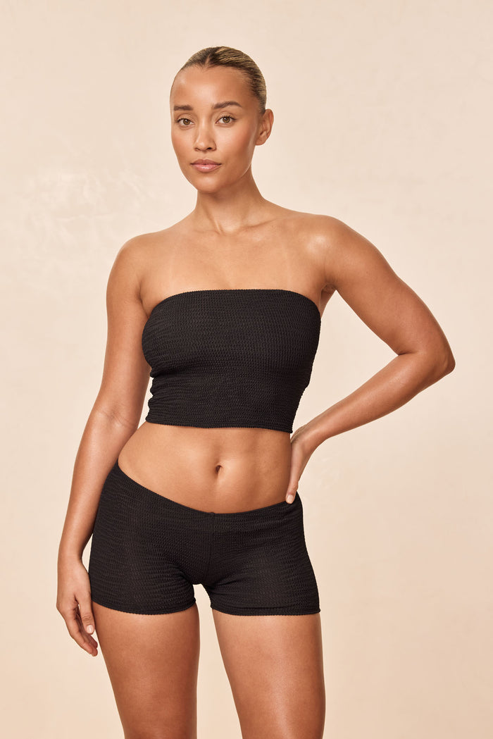 Front view of Laguna Top in Black Crinkle showcasing strapless smocked bandeau fit on model against beige backdrop